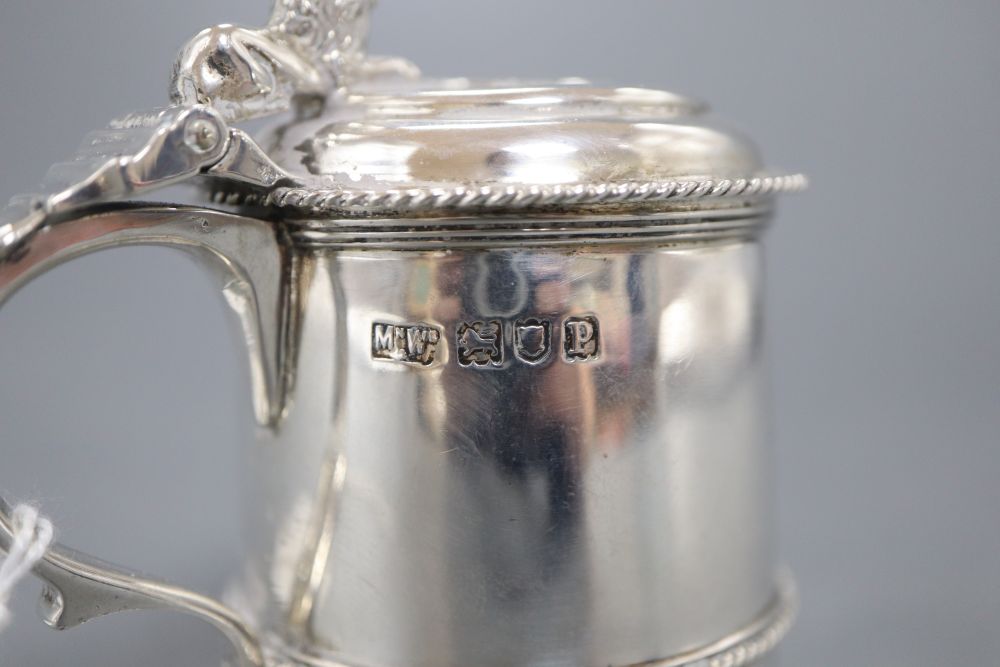 A George V silver mustard pot with blue glass liner, on three recumbent lion feet, Mappin & Webb, London, 1910, 79mm.